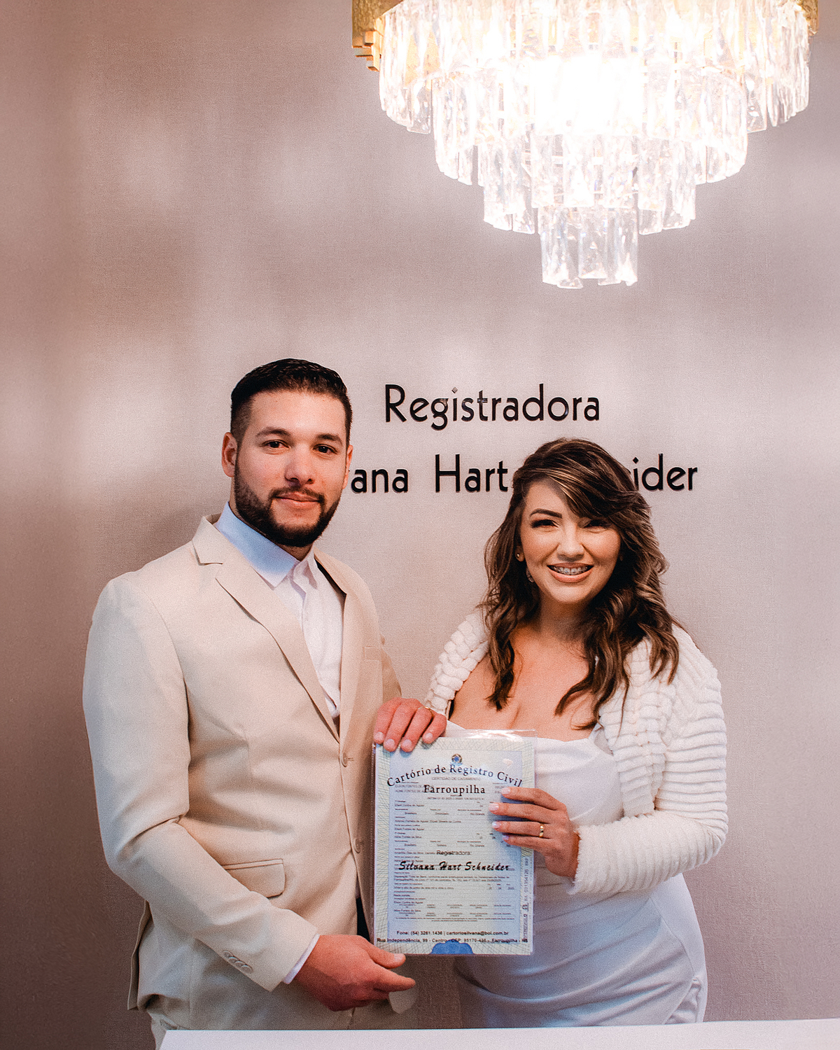 Noivos posam juntos segurando o documento de casamento civil após a cerimônia no cartório de Farroupilha, RS.