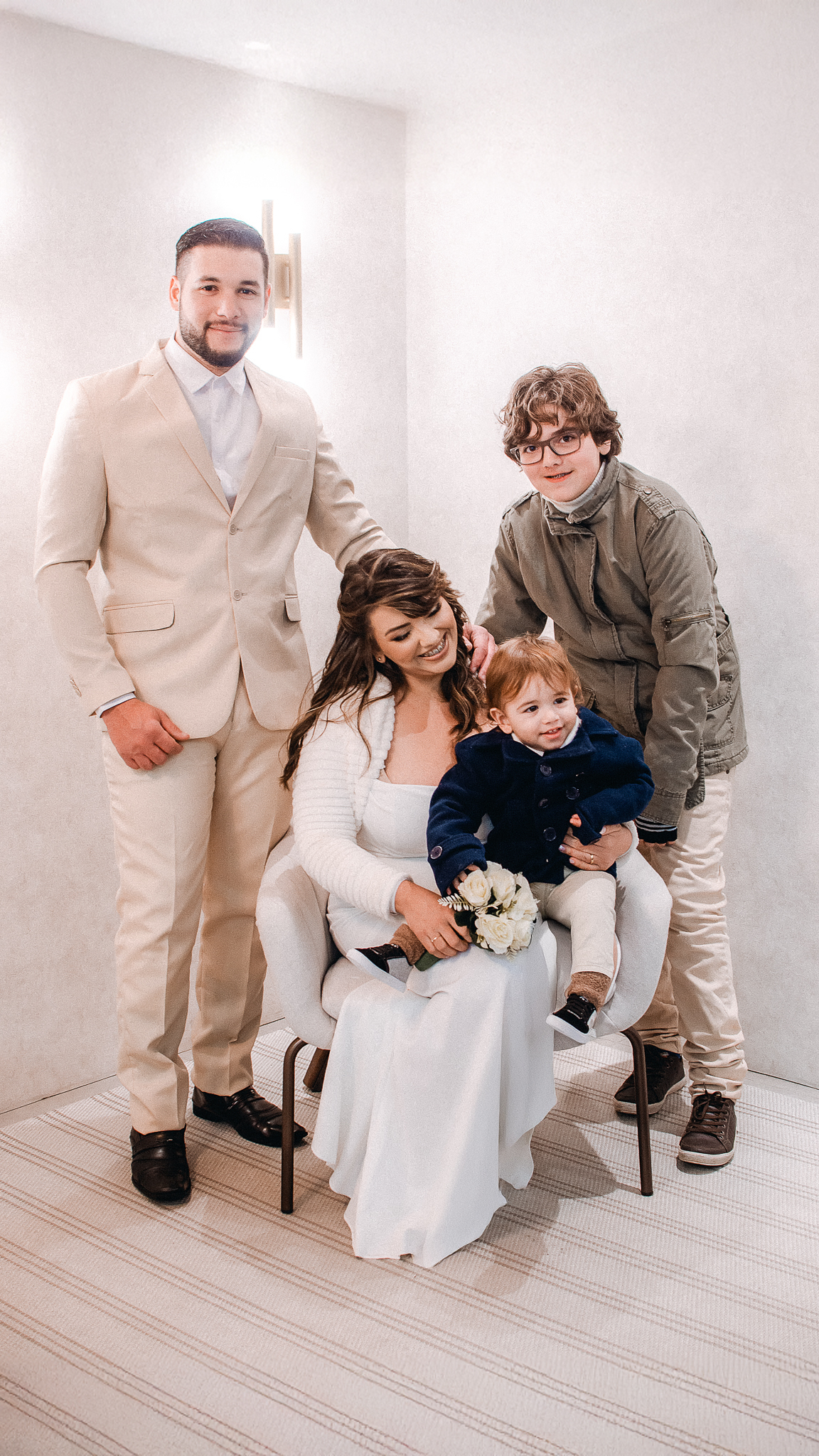 Noiva segura uma criança no colo, acompanhada por familiares, durante os registros fotográficos do casamento civil.