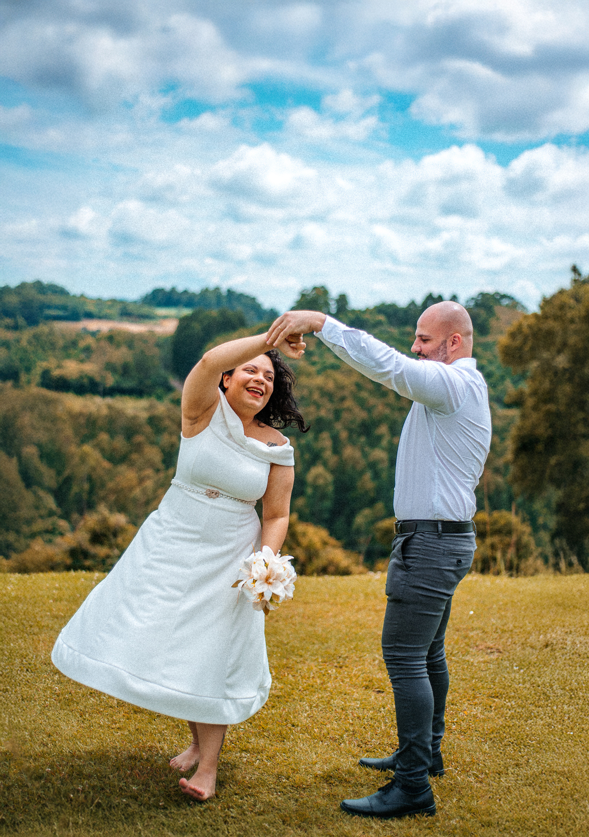 John segura a mão de Stefhanie enquanto ela gira no gramado durante o ensaio externo de casamento em Farroupilha.