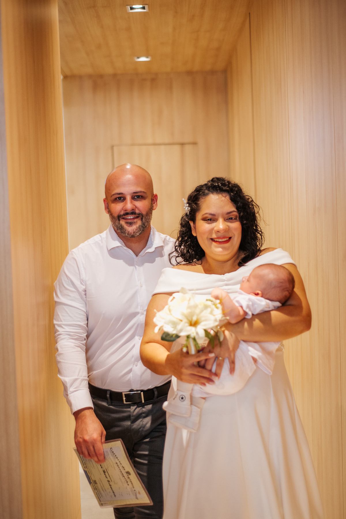 Stefhanie e John posam sorrindo com o bebê nos braços após a cerimônia de casamento civil.