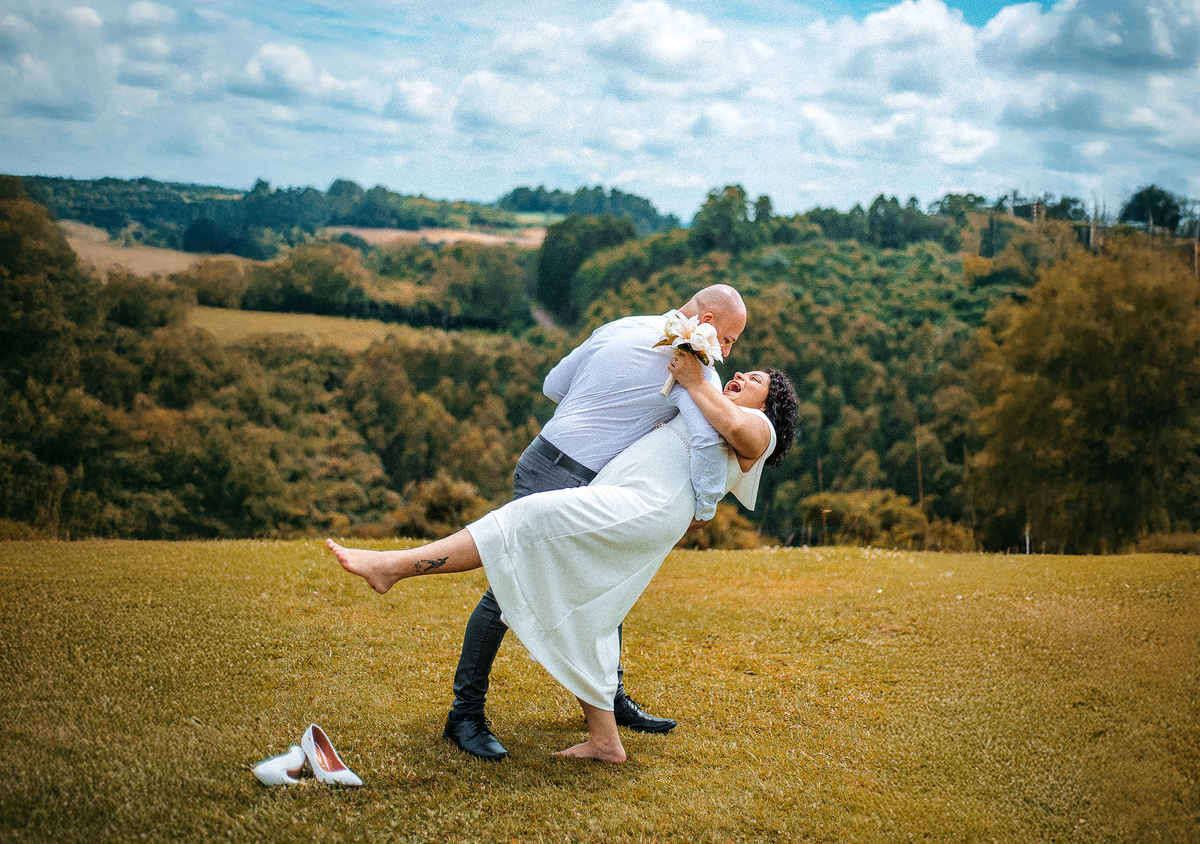 Stefhanie e John em movimento no gramado durante ensaio fotográfico de casamento ao ar livre em Farroupilha.