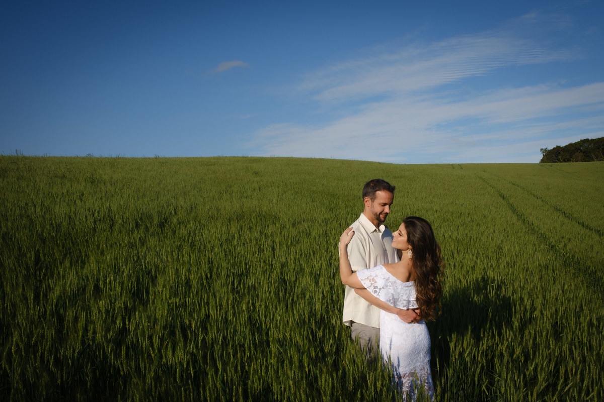 Fotografia do ensaio de casal em capo de trigo no Recanto Nogarotto em São José dos Pinhais com a noiva abraçada com o noivo no terço inferior direito da imagem