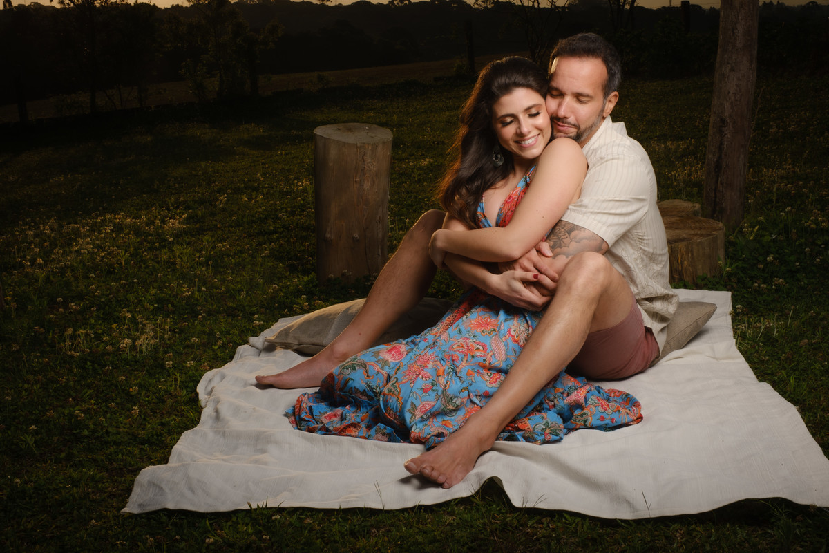 Noivo abraça a noiva pela cintura com a cabeça no ombro da noiva e a noiva com os olhos fechados e sorrindo por receber o carinho do noivo durante o ensaio de casal no Recanto Nogarotto em São José dos Pinhais