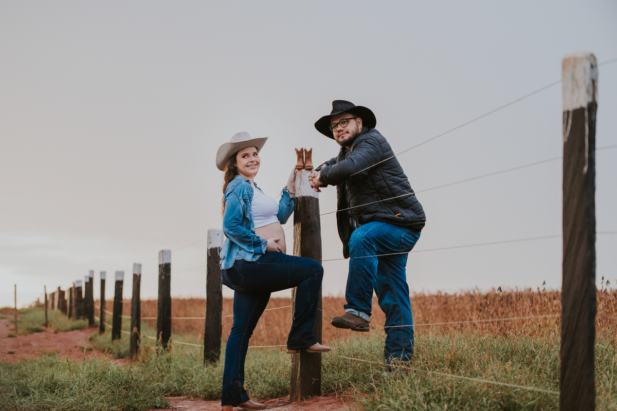 Foto com pais em sintonia à espera do bebê em cenário rural encantador.

