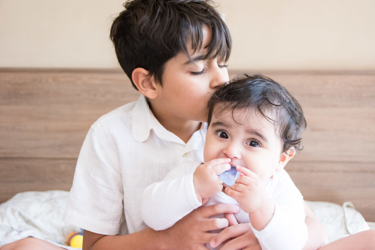 Carinho de irmão, amor de irmãos, irmão beijando o bebê