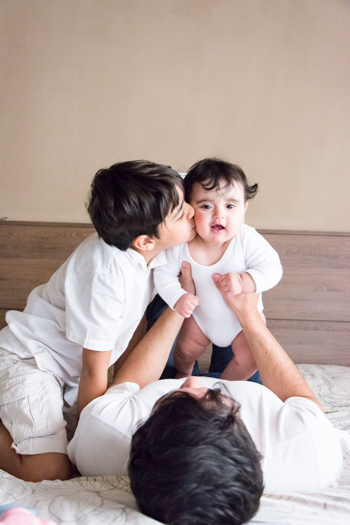 Irmãozinho beijando o bebê e papai segurando o bebê