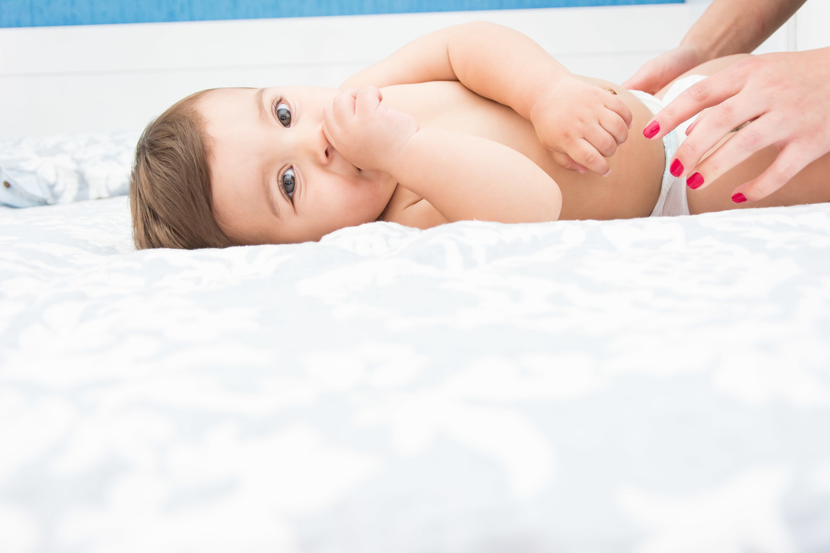 bebê chupando o dedo na cama da mãe