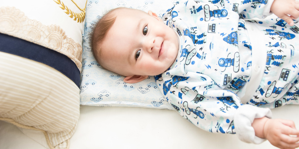 bebê de pijama sorrindo no berço