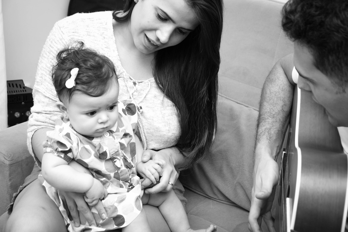 mamãe e bebê no sofá ouvindo o papai tocando violão