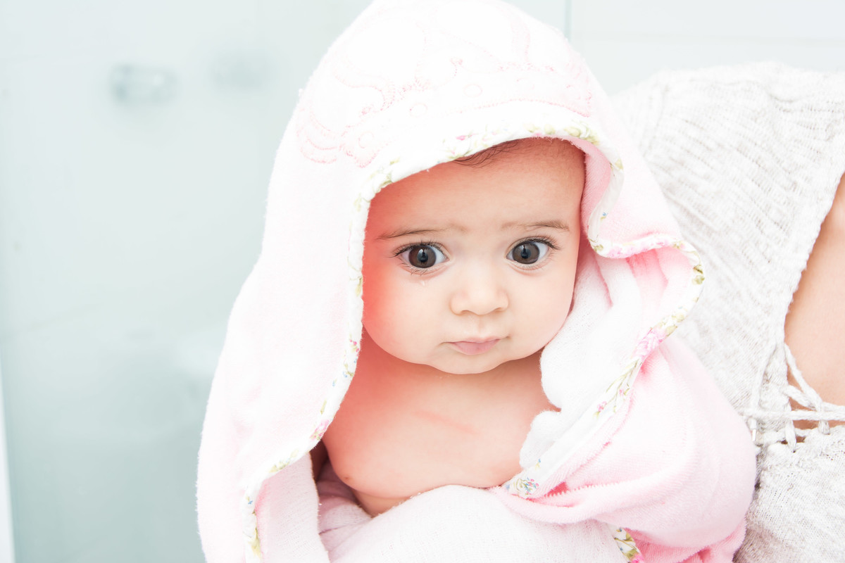 Bebê de toalha com touca depois do banho, bebê com olhão