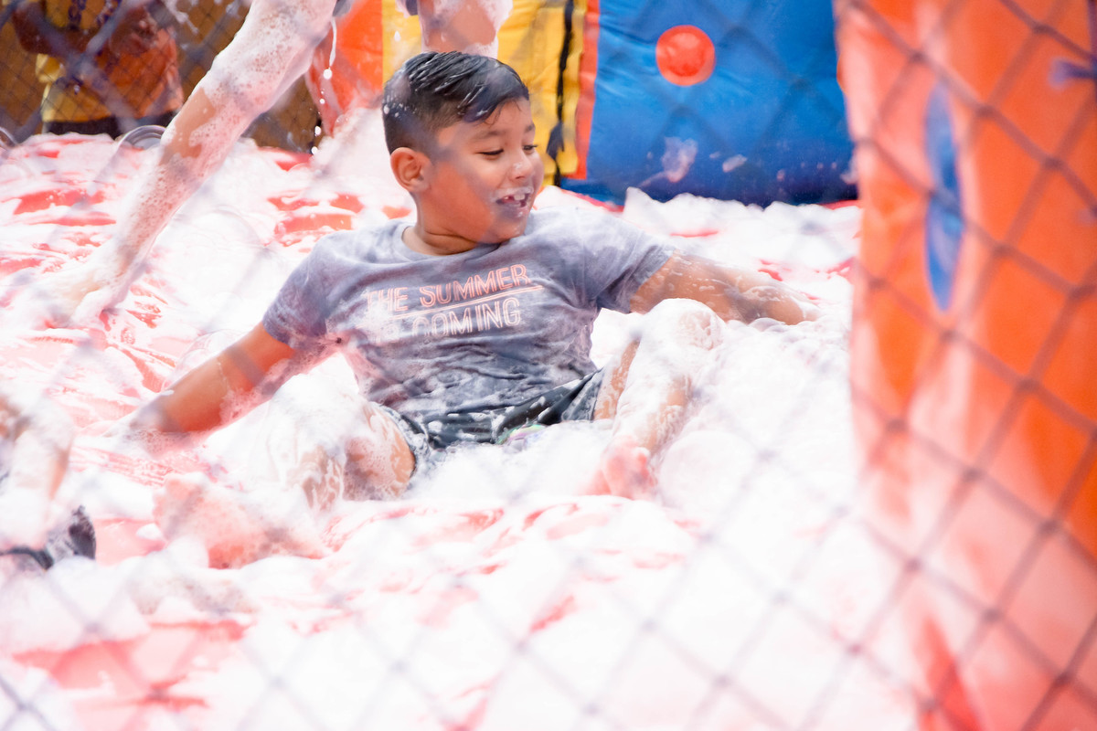 Criança brincando na chuva jogando futebol de sabão