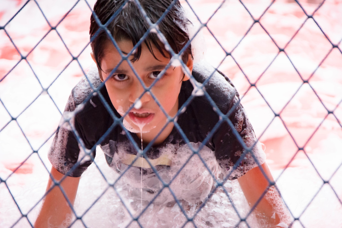 Criança brincando na chuva jogando futebol de sabão