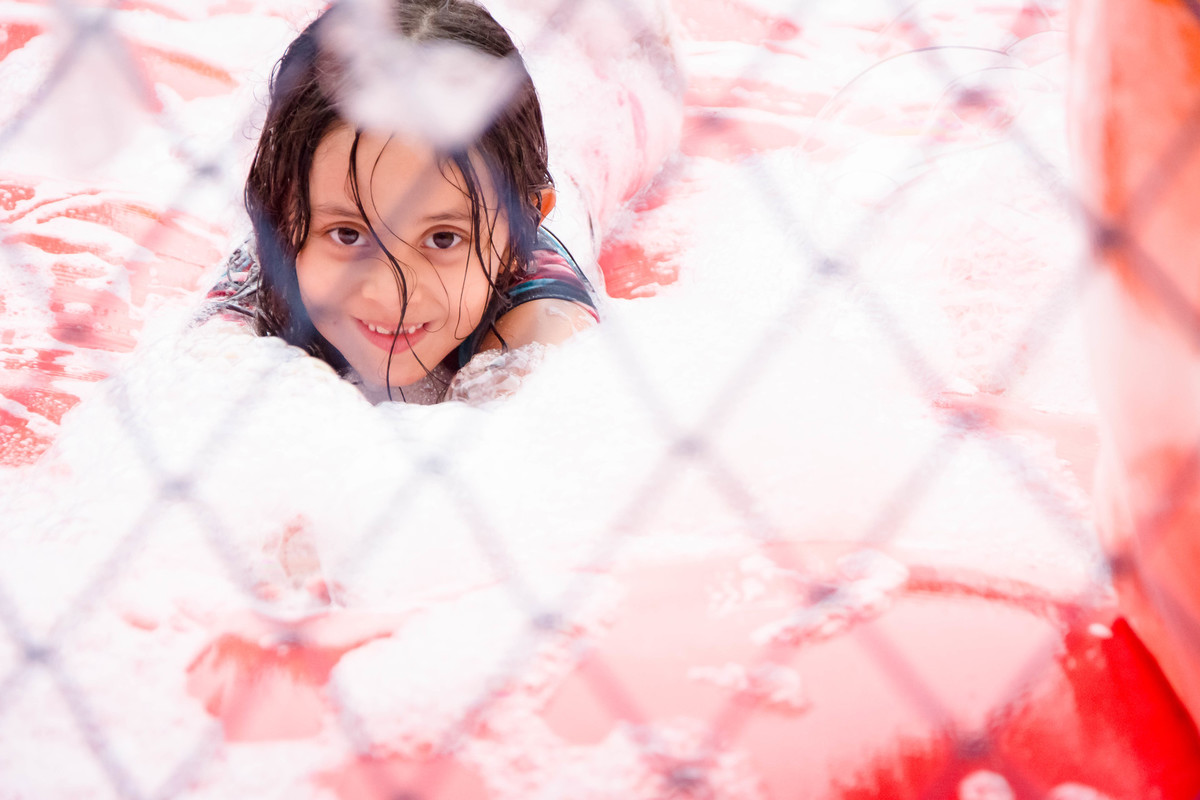 Criança brincando na chuva jogando futebol de sabão