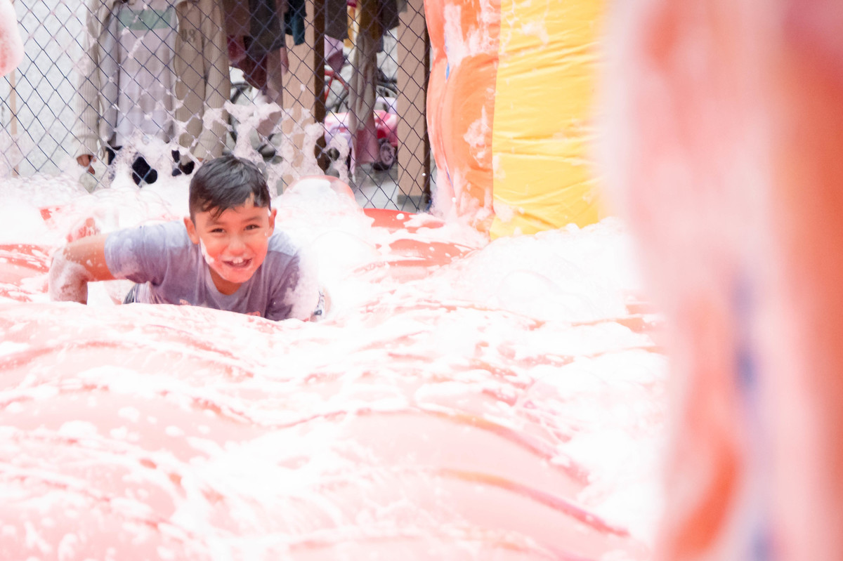 Criança brincando na chuva jogando futebol de sabão