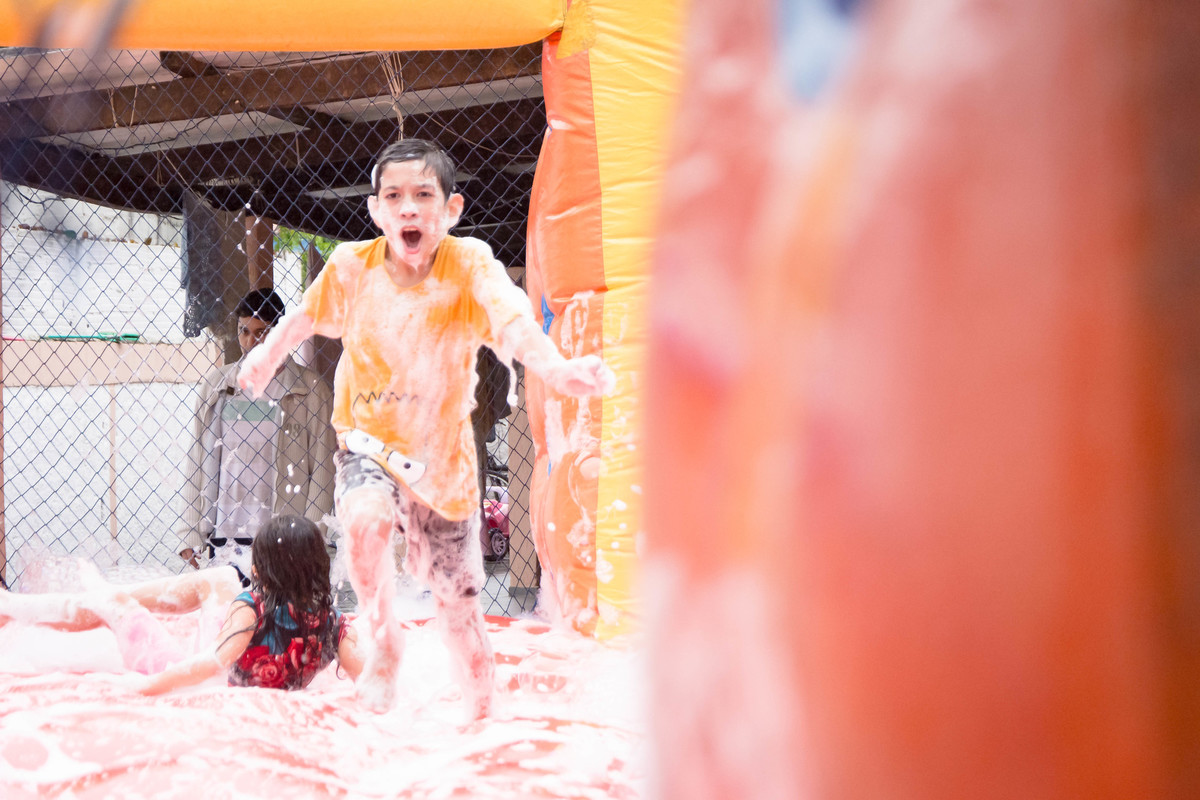 Criança brincando na chuva jogando futebol de sabão
