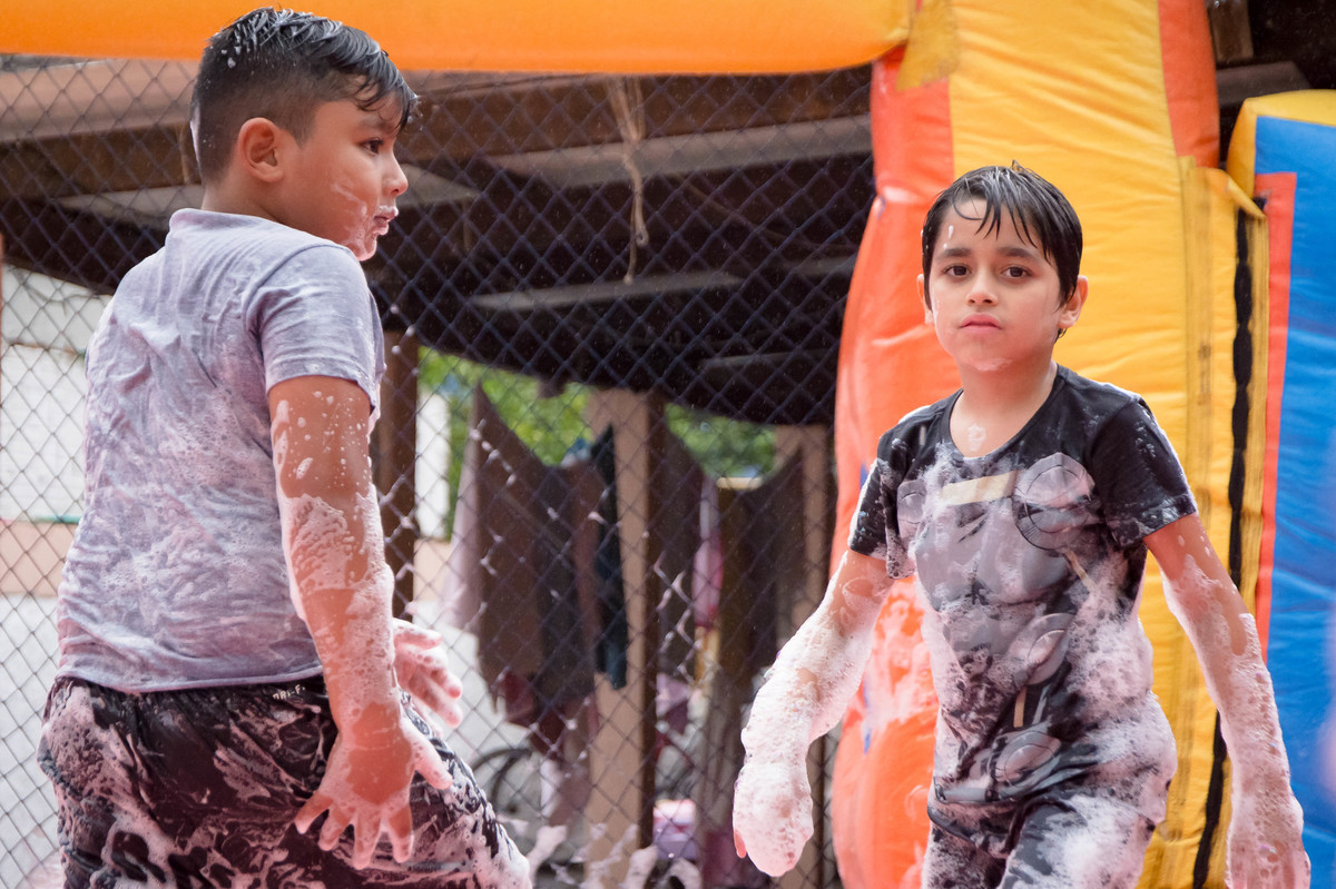 Criança brincando na chuva jogando futebol de sabão