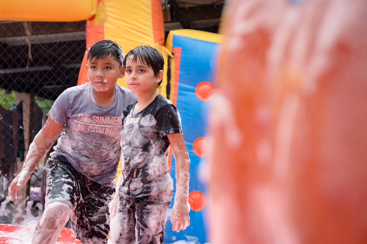 Criança brincando na chuva jogando futebol de sabão