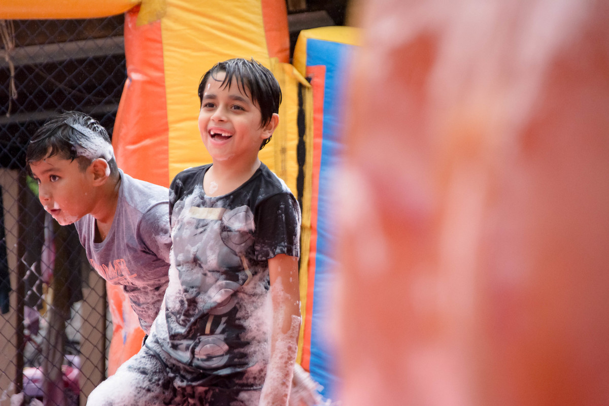 Criança brincando na chuva jogando futebol de sabão