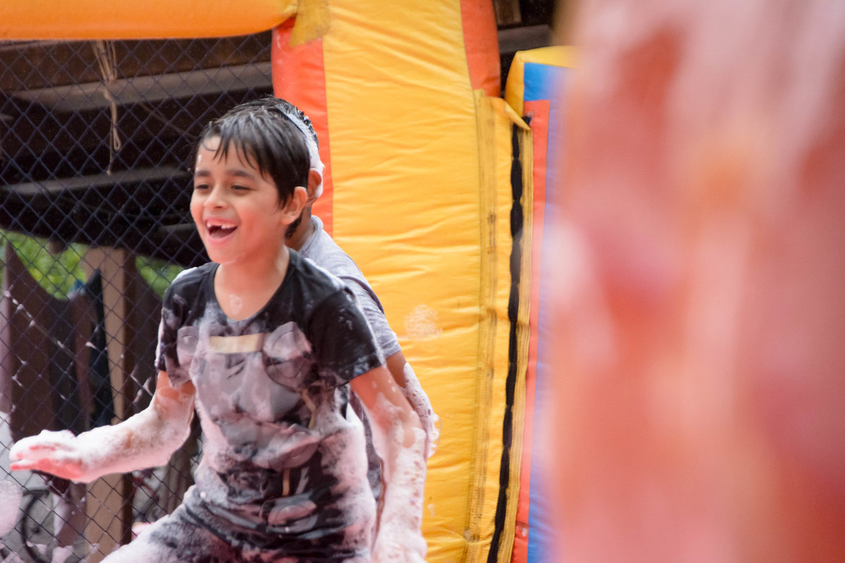 Criança brincando na chuva jogando futebol de sabão