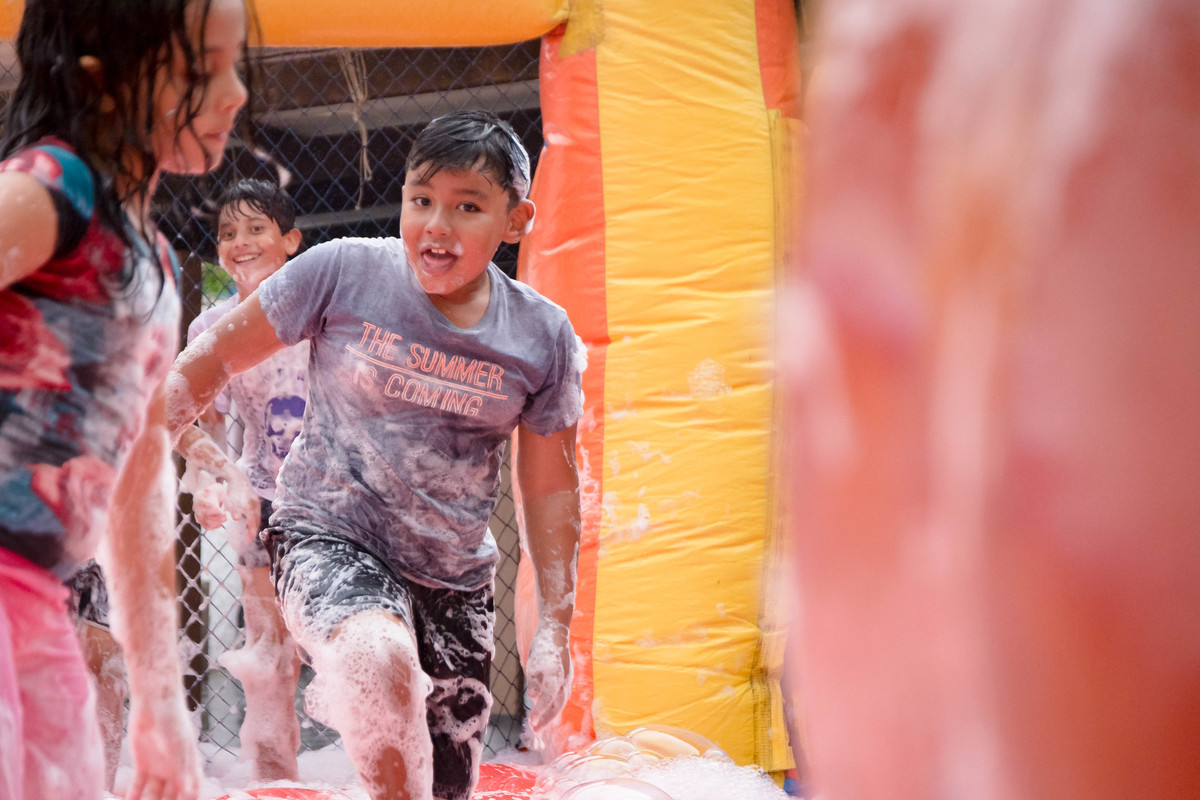 Criança brincando na chuva jogando futebol de sabão