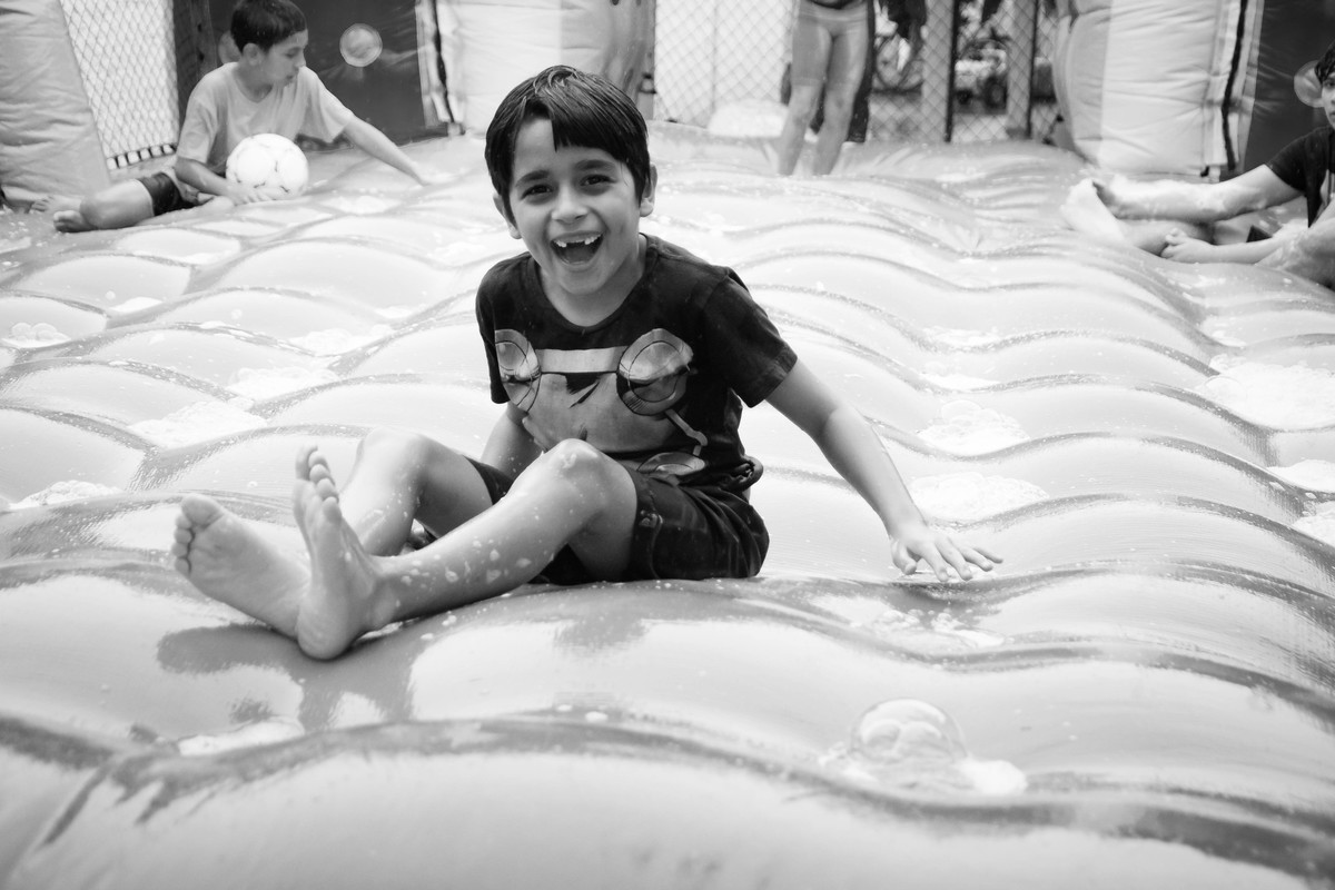 Criança brincando na chuva jogando futebol de sabão