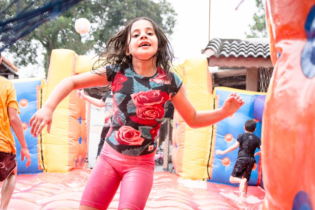 Criança brincando na chuva jogando futebol de sabão