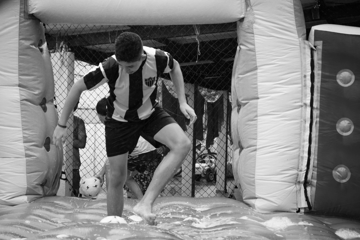 Criança brincando na chuva jogando futebol de sabão