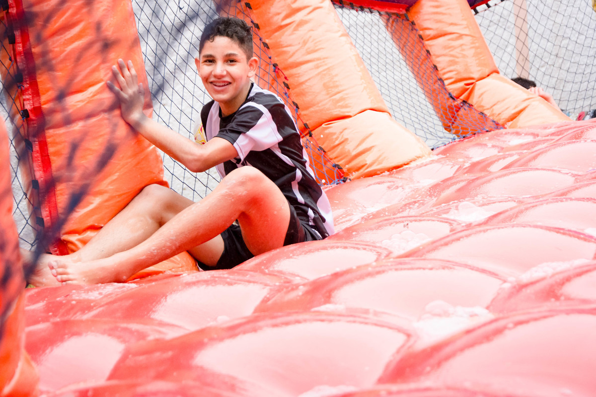 Criança brincando na chuva jogando futebol de sabão