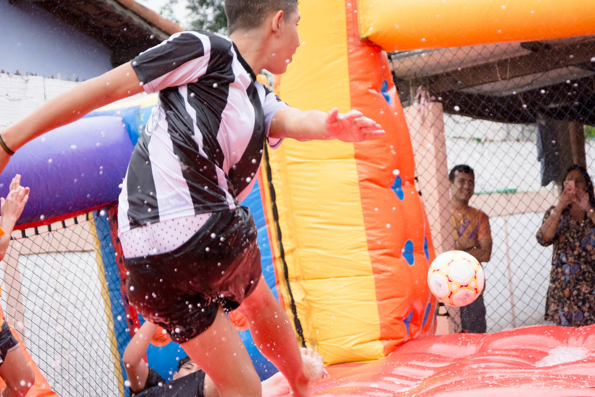 Criança brincando na chuva jogando futebol de sabão