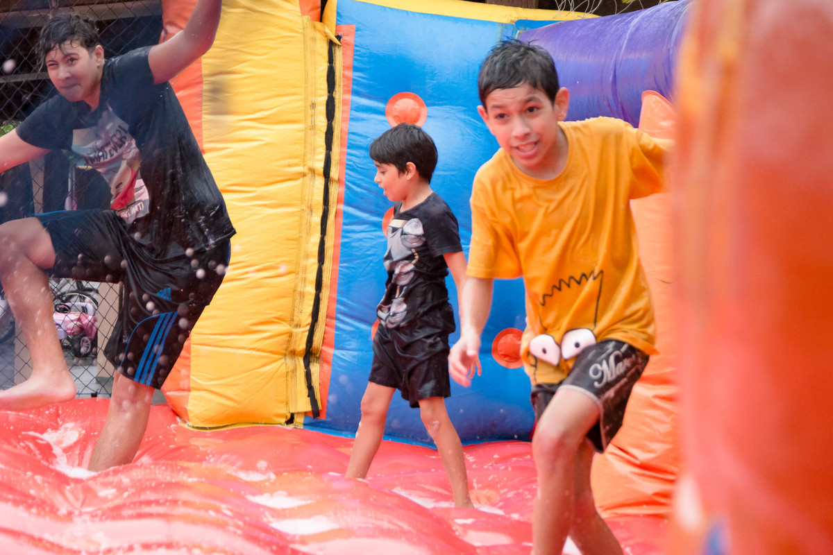 Criança brincando na chuva jogando futebol de sabão