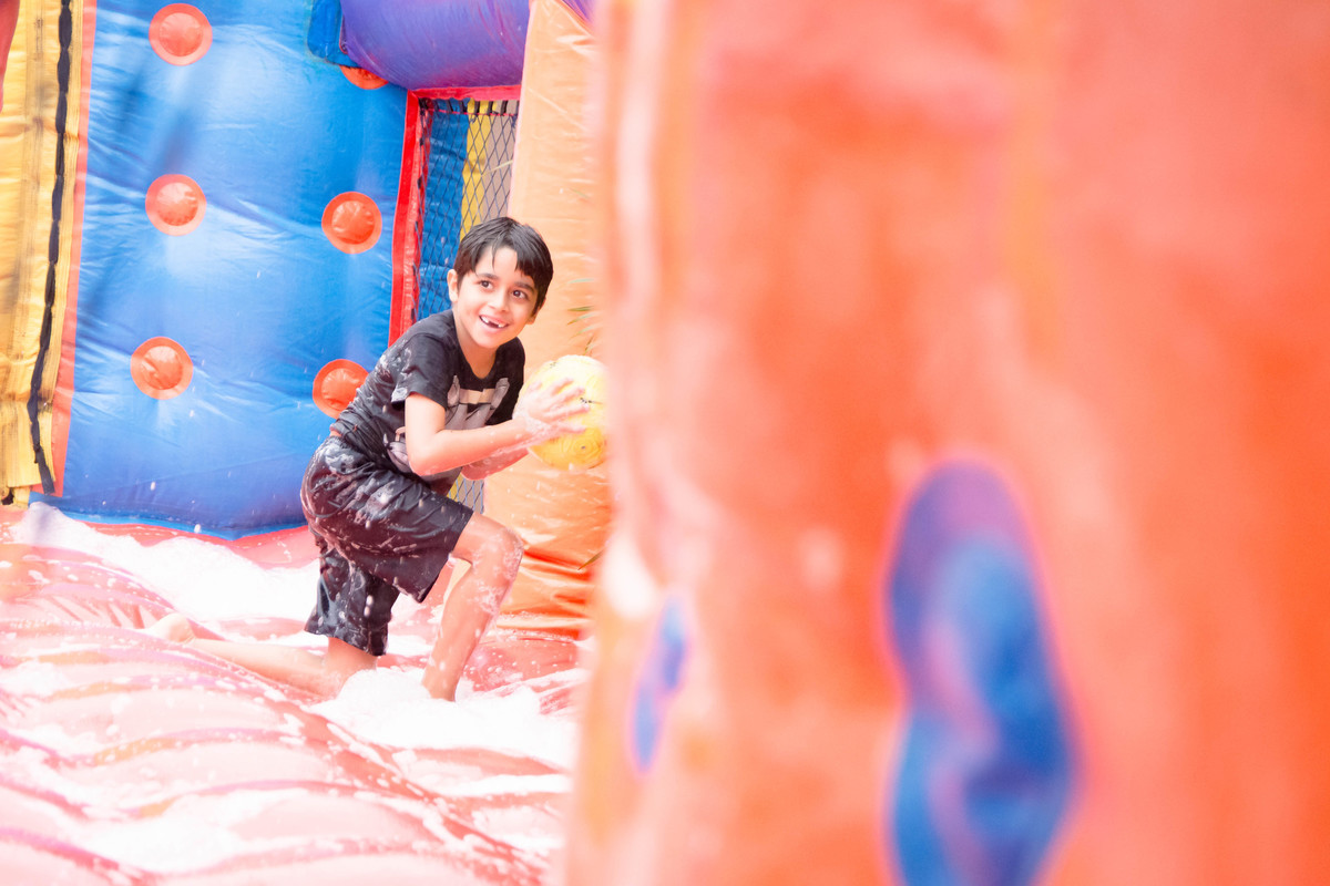 Criança brincando na chuva jogando futebol de sabão