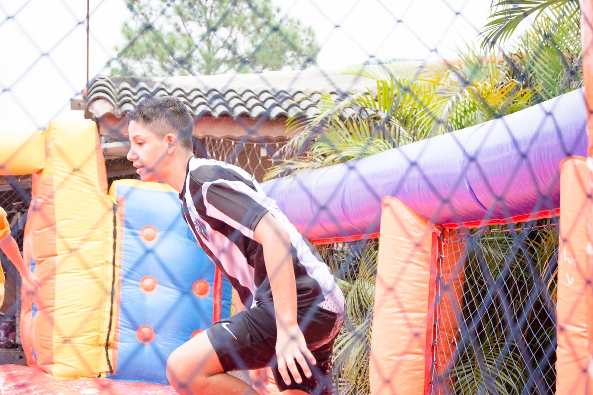 Criança brincando na chuva jogando futebol de sabão