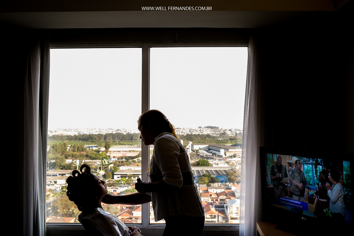 nova se maquiando em frente a janela