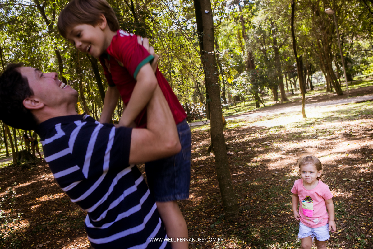 pai levantando seu filho enquanto sua irmanzinha olha