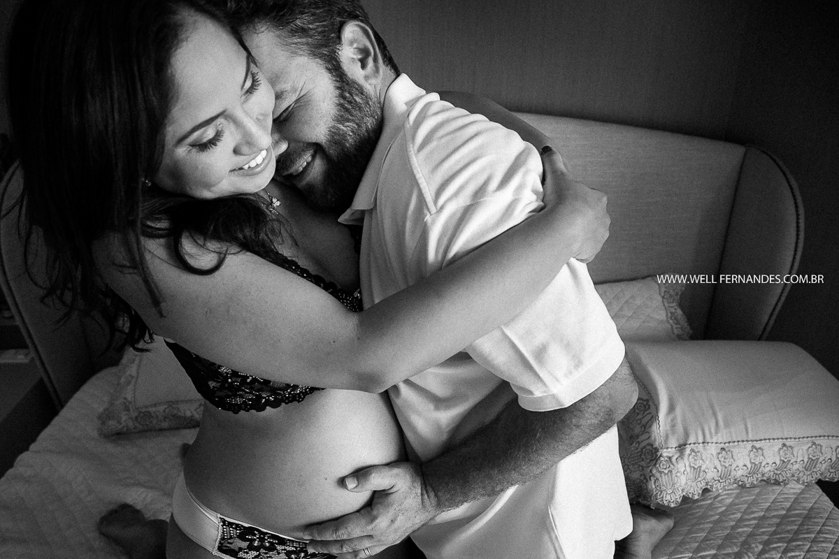 casal gravidos sorrindo em cima da cama