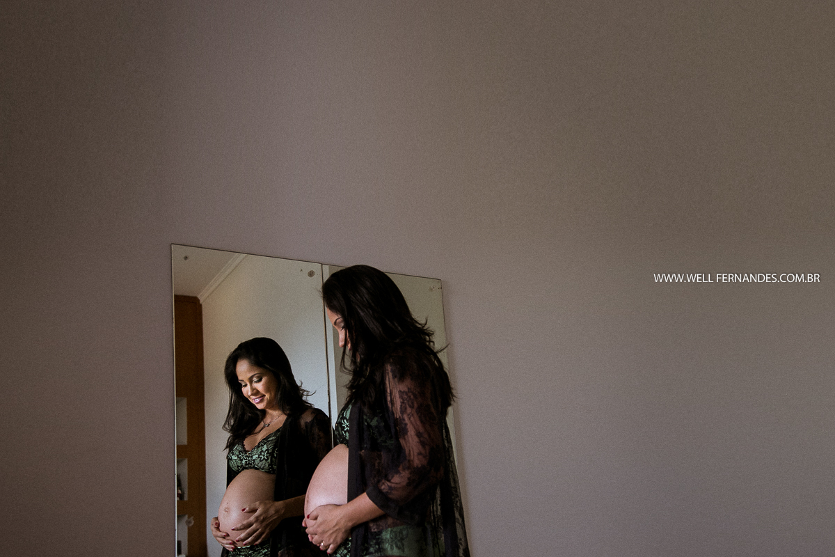 mulher gravida admirando a barriga em frente ao espelho
