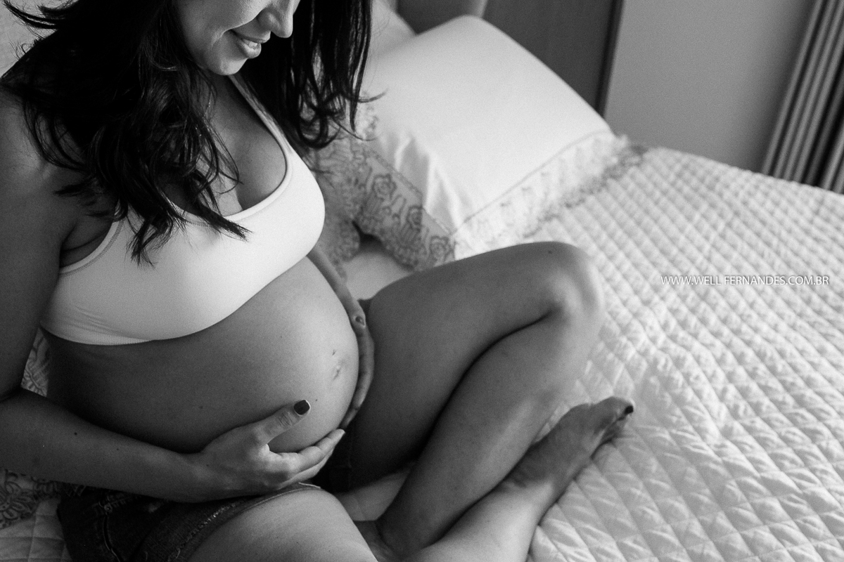 gestante segurando a sua barriga em cima da cama