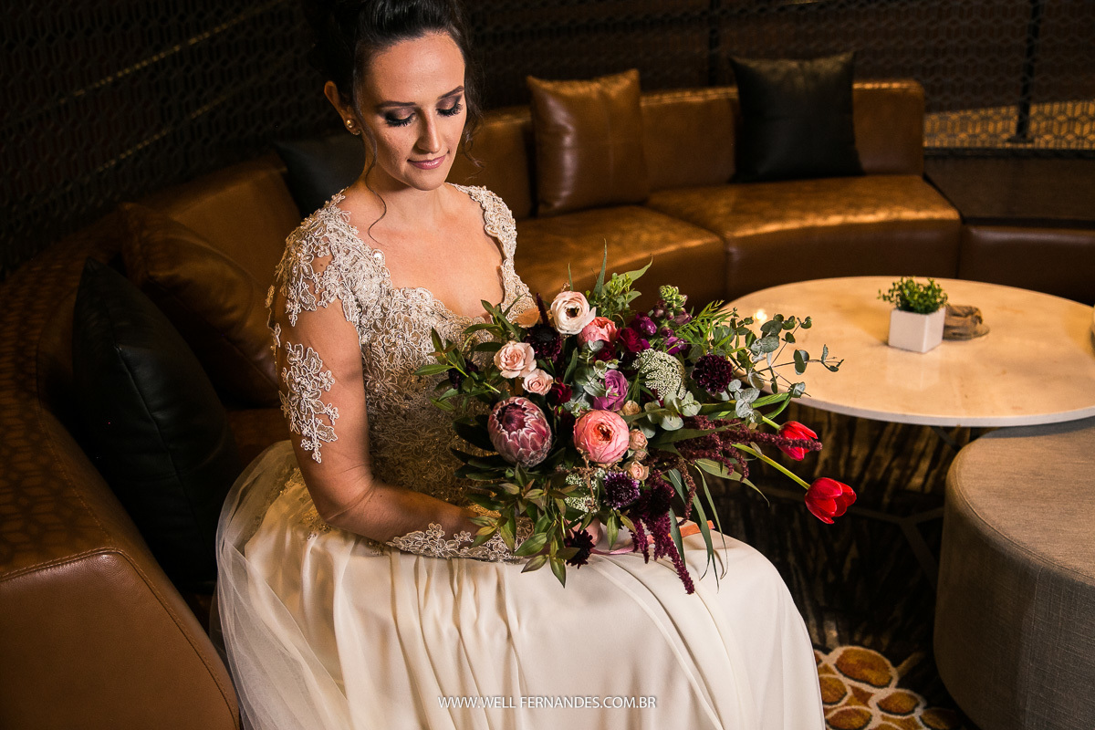 noiva sentada admirando o seu bouquet