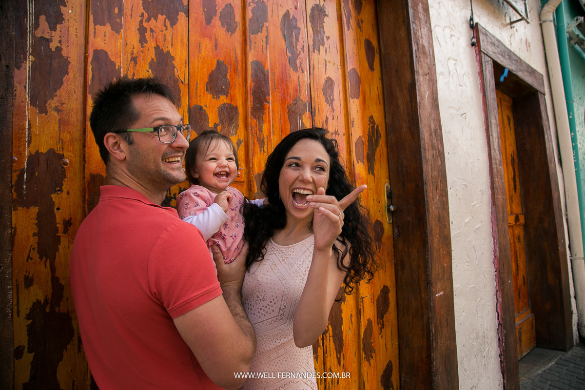 pai, mae e filha olhando e rindo