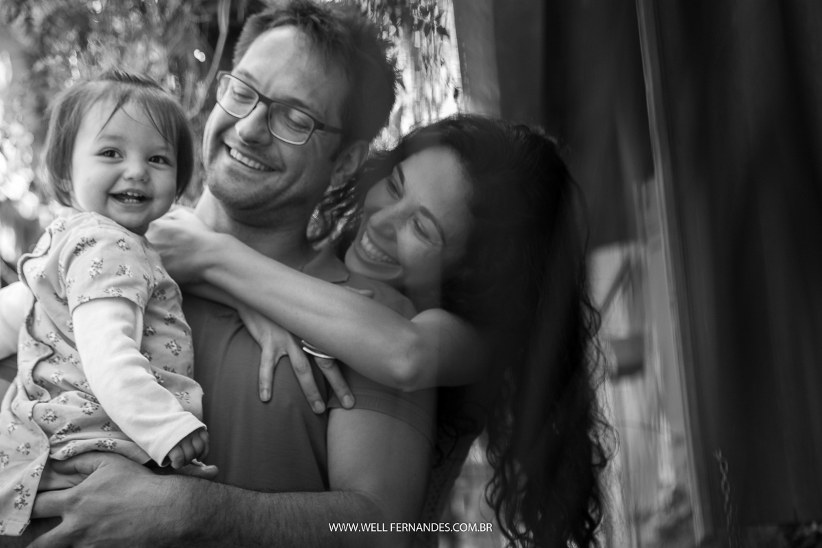 mae abraçando o marido e a filha sorrindo