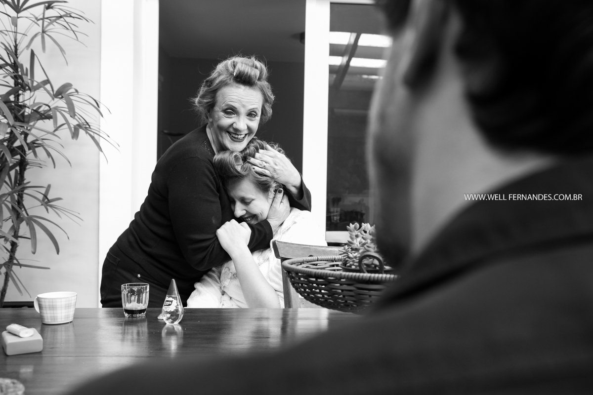 mae abraçando a noiva em sua casa