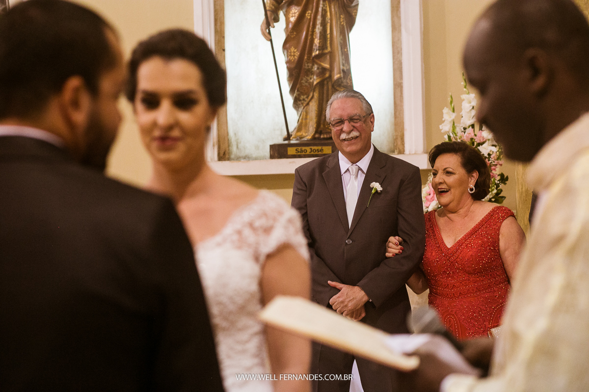 pais da noiva sorrindo no altar