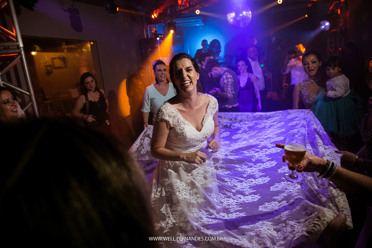 convidados segurando o vestido da noiva e rodando