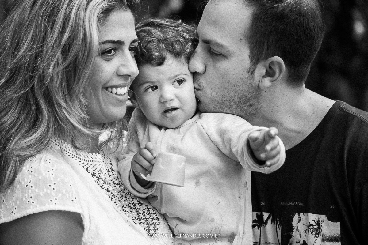 pai e mae abraçando e beijando a filha