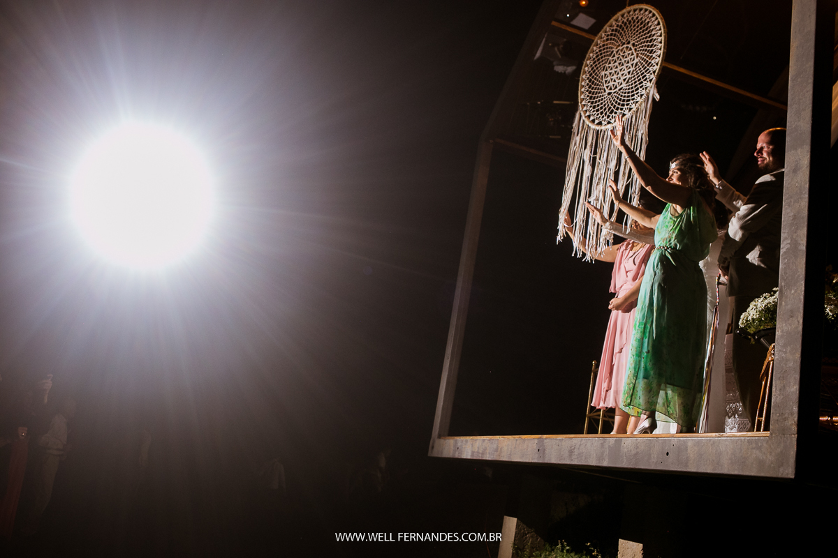 noivos e demais convidados agradecendo e estendendo a mão depois dos convidados jogarem as pedrinhas no mar