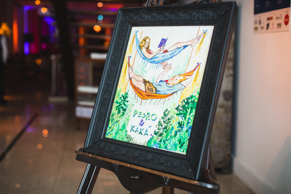 Quadro com a caricatura dos noivos Karine e Pedro na entrada da recepção na Galeria Scenarium/Rio Scenarium, Rio de Janeiro/RJ