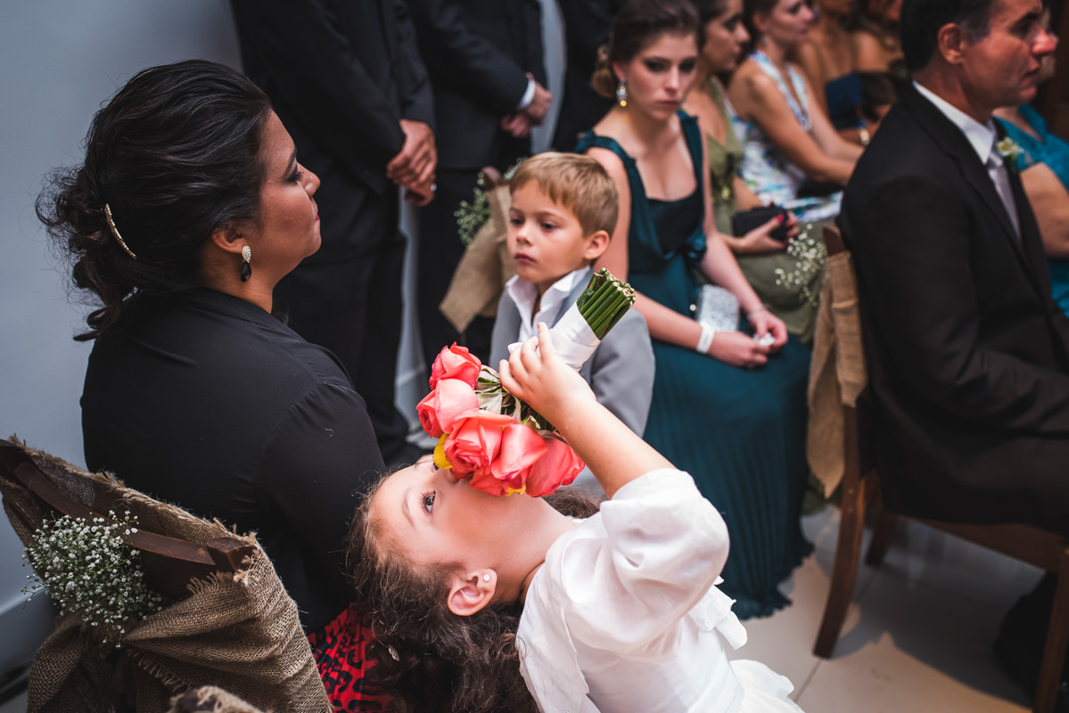 A daminha brincando com o buquê da noiva na cerimônia do casamento de Karine e Pedro na Galeria Scenarium/Rio Scenarium, Rio de Janeiro/RJ