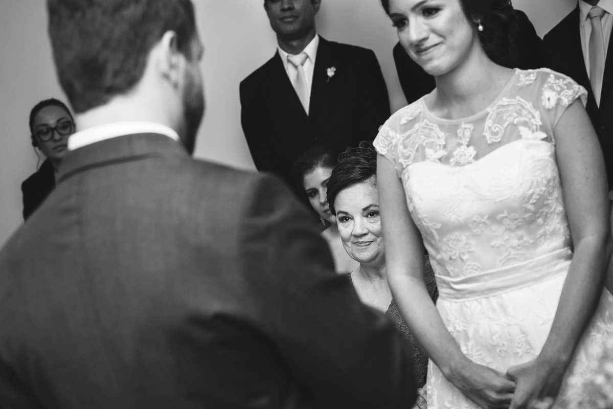 A mãe da noiva observando emocionada os votos do noivo Pedro para sua filha Karine na cerimônia do casamento na Galeria Scenarium/Rio Scenarium, Rio de Janeiro/RJ