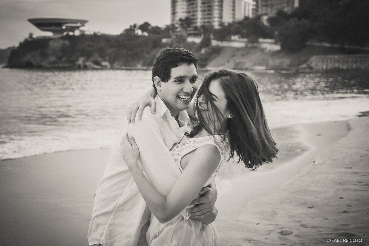 Momento descontraído do casal Mariana e Israel no ensaio pré-casamento na Praia de Icaraí, Niterói/RJ