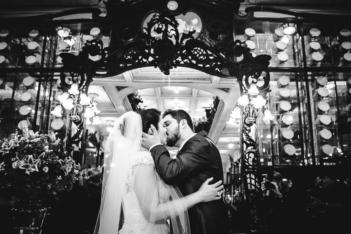 Foto preta e branca do beijo no casamento dos noivos Débora e Leonardo Guimarães Joias na Confeitaria Colombo, Centro, Rio de Janeiro-RJ